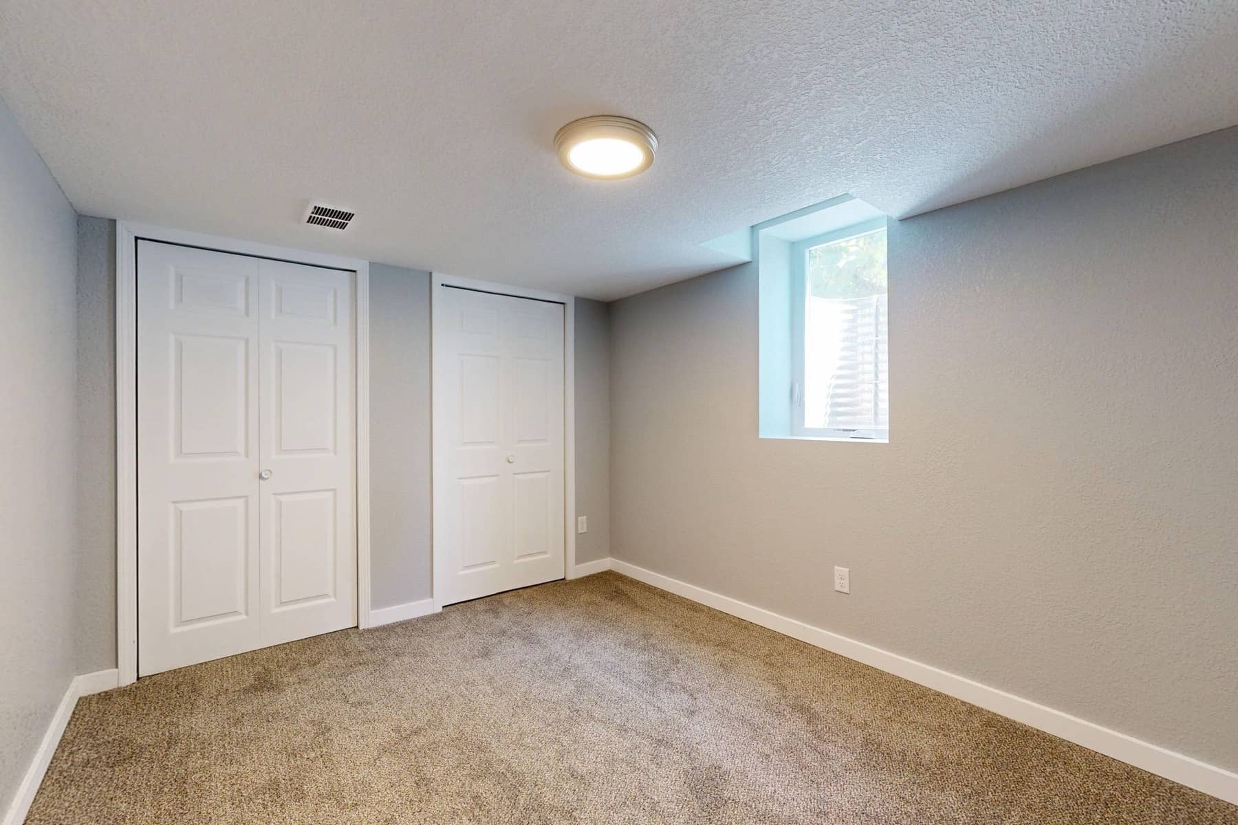 Carpeted basement bedroom with a casement window set into a steel window well, Sioux Falls area