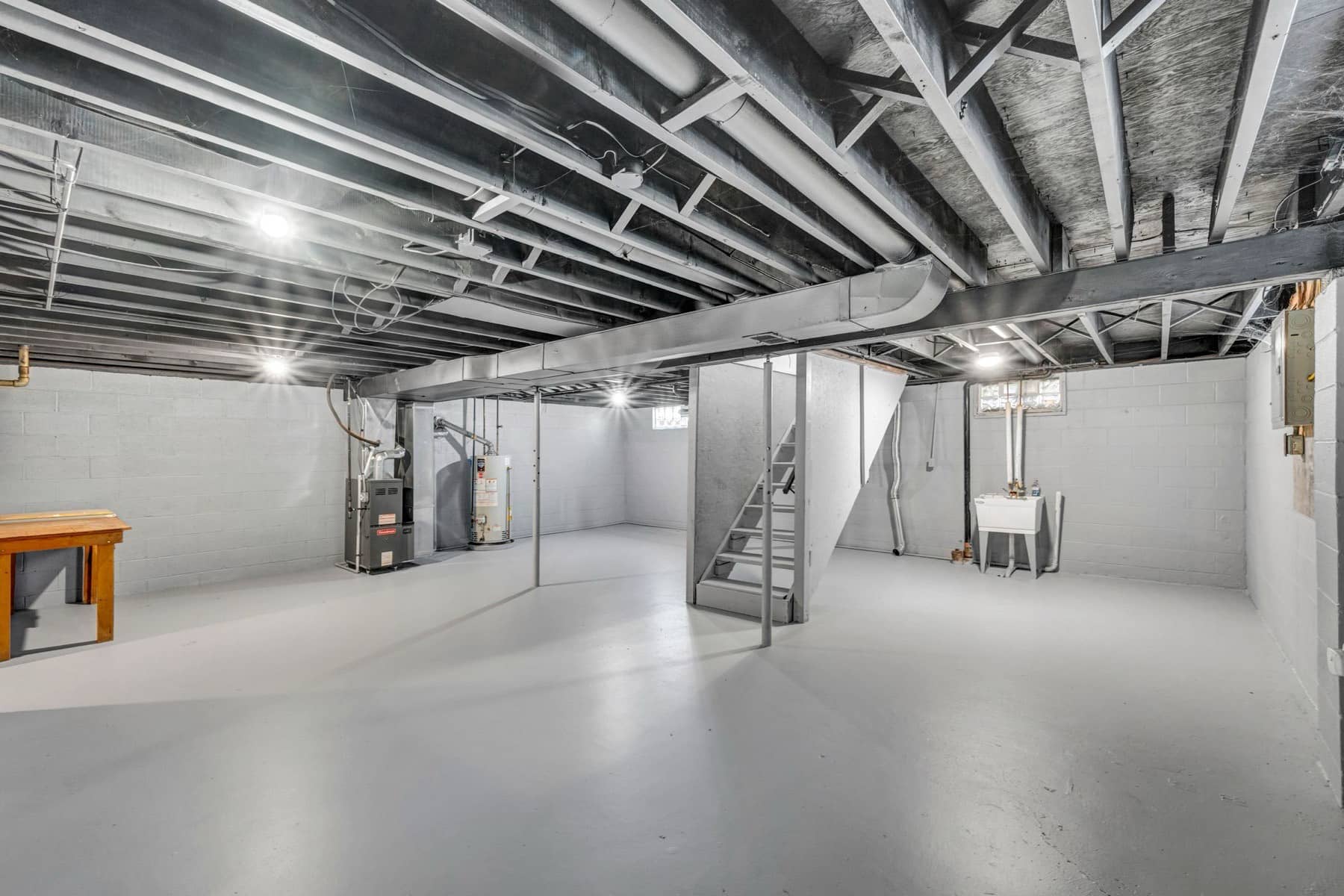 Unfinished basement with painted block walls, a painted concrete floor, open joists, a furnace, and a water heater, Sioux Falls area